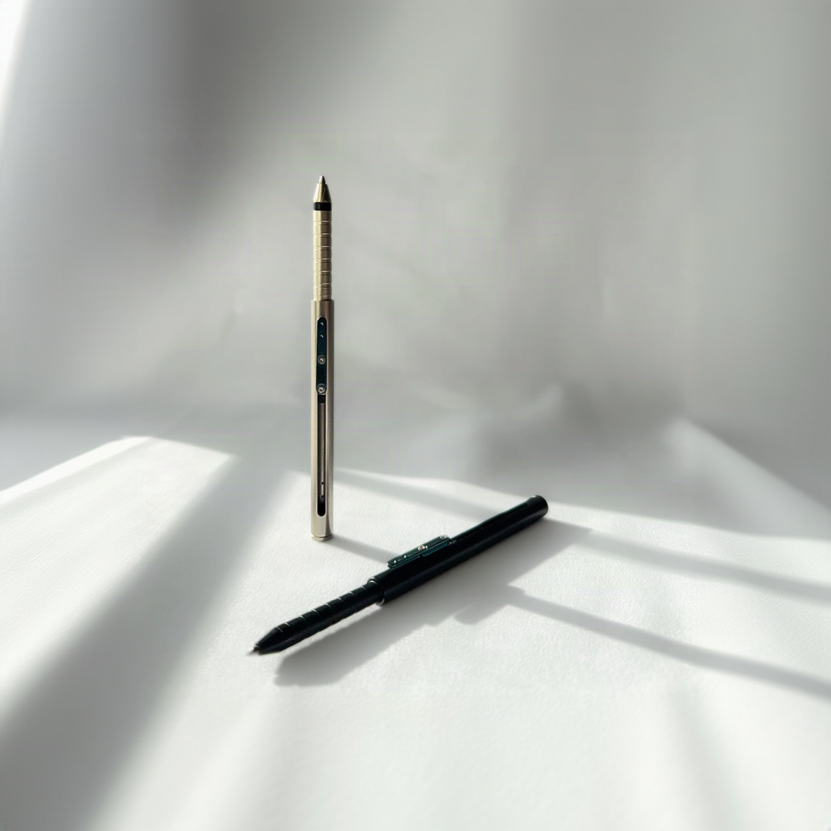 Two pens, one gold and one black, on a white surface with soft shadows.