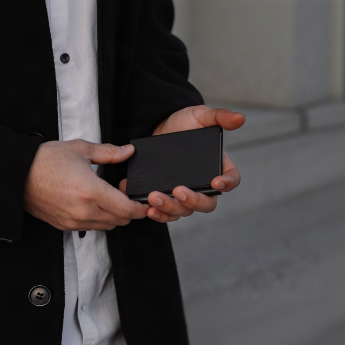 Person holding a black wallet with a neutral background